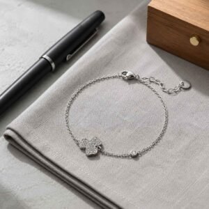 Close-up of a premium lucky clover bracelet made of polished surgical stainless steel featuring a detailed three-leaf shamrock charm, 24h sound-bath calibrated at 528Hz, displayed inside the signature Luxe Abundance Box.