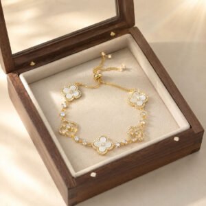 Close-up of a handcrafted red four-leaf clover bracelet in gold, parisian chic quiet luxury style, 24h sound-bath calibrated at 528Hz for 2026 social magnetism, displayed inside the white Luxe Abundance Box.