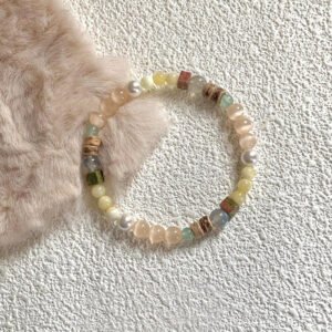 Natural peach cat’s eye stone bracelet with white pearls on a frosted glass plate