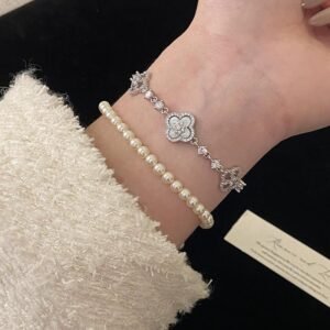 Elegant white clover bracelet stacked with a pearl bracelet on a wrist